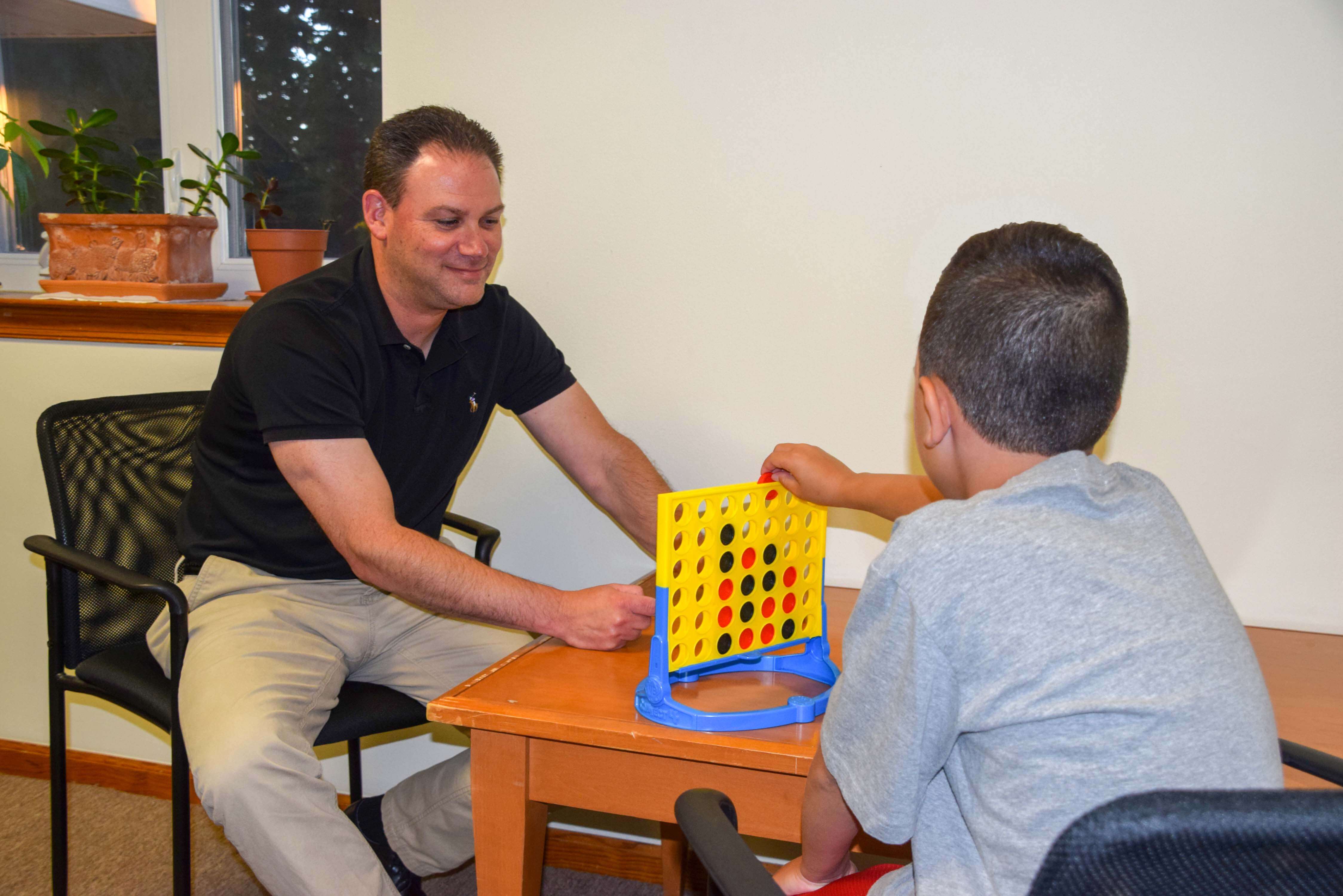 A young boy putting a Connect Four piece into the grid in a game with Joel Sperling